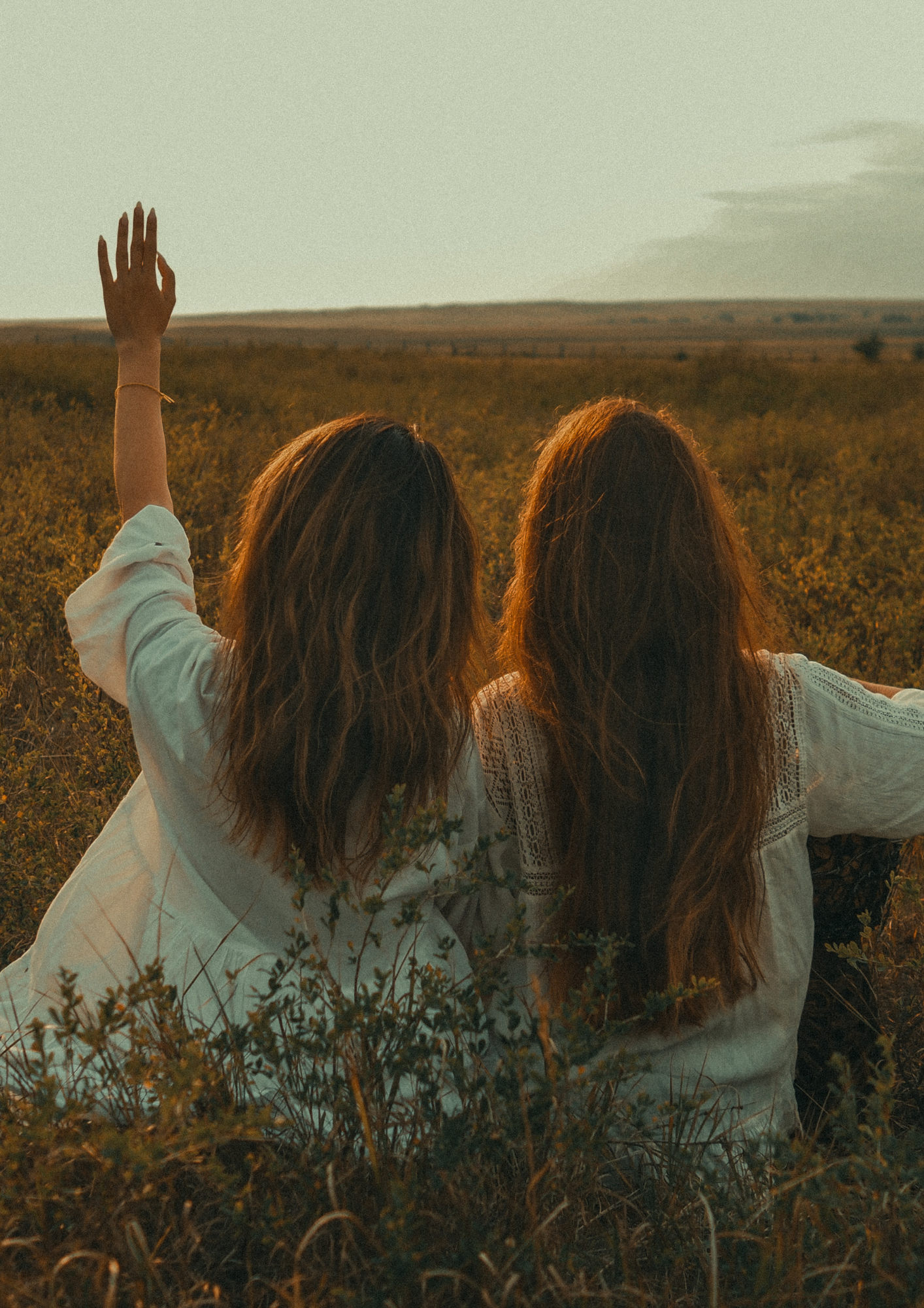 Zwei Frauen sitzen mit dem Rücken zum Fotografen auf einem Feld.
